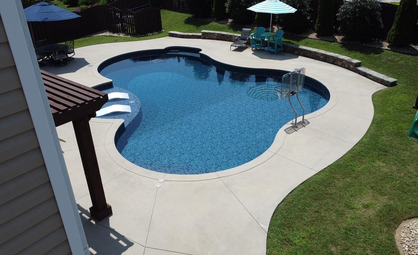 Aerial view of freeform vinyl pool with tanning shelf